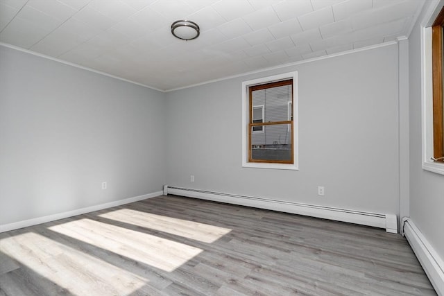 spare room with light wood-type flooring, ornamental molding, and baseboard heating