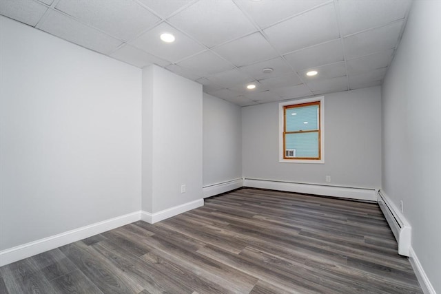 unfurnished room featuring a baseboard heating unit, a drop ceiling, and dark hardwood / wood-style flooring