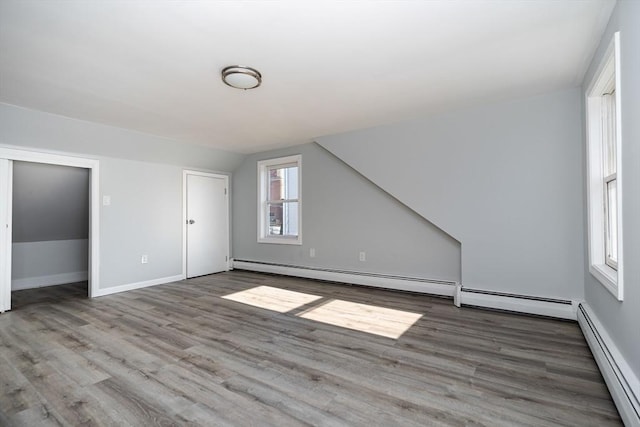 additional living space featuring lofted ceiling, a baseboard heating unit, and hardwood / wood-style floors