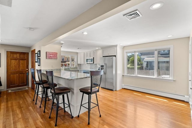 12 Shore Ave, Salem, MA 01970 - kitchen featuring stainless steel appliances, a baseboard radiator, a peninsula, light wood-style floors, and a kitchen bar