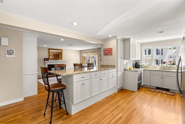 12 Shore Ave, Salem, MA 01970 - kitchen featuring a peninsula, light wood-style floors, recessed lighting, a kitchen breakfast bar, and light stone countertops