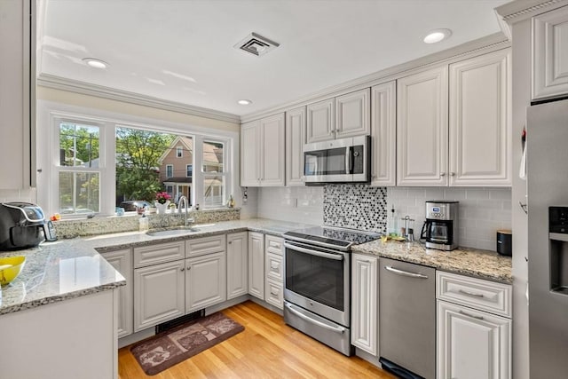 12 Shore Ave, Salem, MA 01970 - kitchen with stainless steel appliances, ornamental molding, tasteful backsplash, light wood-style floors, and light stone countertops