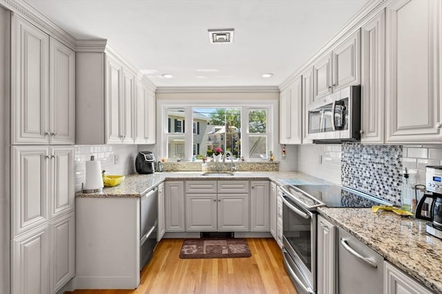 12 Shore Ave, Salem, MA 01970 - kitchen featuring appliances with stainless steel finishes, light wood finished floors, light stone counters, tasteful backsplash, and recessed lighting