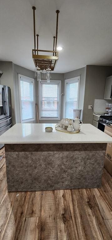 8 Suffield St, Worcester, MA 01610 - kitchen with wood finished floors, black gas range, light countertops, a center island, and freestanding refrigerator
