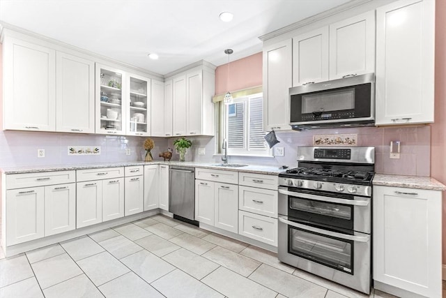 kitchen with appliances with stainless steel finishes, glass insert cabinets, and white cabinetry