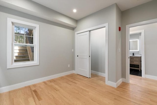 unfurnished bedroom featuring a closet, sink, and light hardwood / wood-style flooring