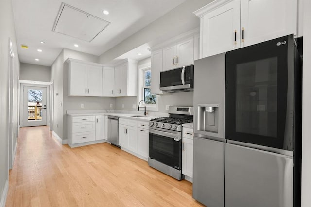 kitchen featuring stainless steel appliances, a wealth of natural light, light wood-type flooring, and white cabinets