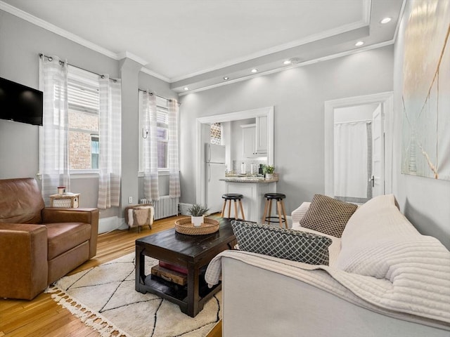 living room with ornamental molding, radiator heating unit, and light wood-type flooring