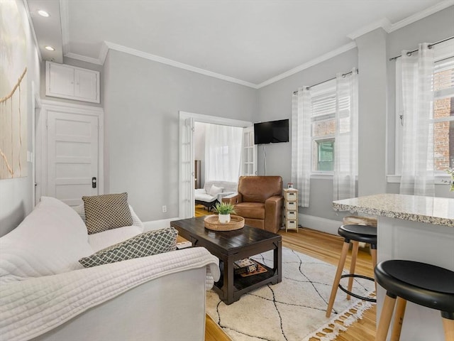 living room with crown molding, plenty of natural light, and light hardwood / wood-style floors