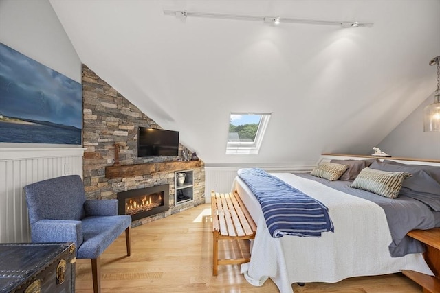 10 Seashore Park Dr Unit Gg, Provincetown, MA 02657 - bedroom with vaulted ceiling, a fireplace, light wood-style floors, a wainscoted wall, and a skylight