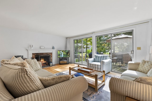 living room with a wealth of natural light, a brick fireplace, and hardwood / wood-style flooring