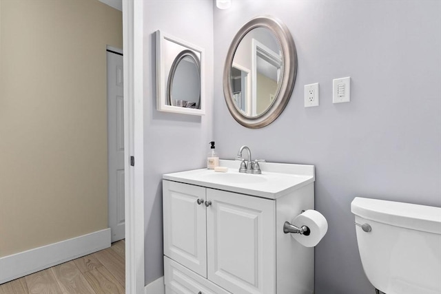 bathroom with wood finished floors, toilet, vanity, and baseboards