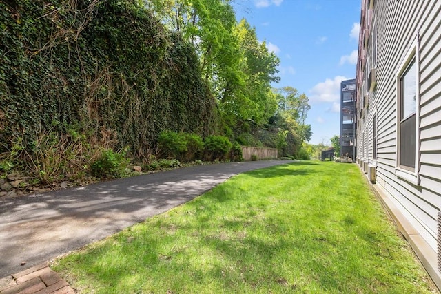 view of green lawn featuring asphalt driveway