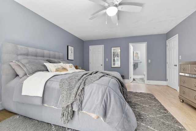 bedroom featuring wood finished floors, ensuite bathroom, a ceiling fan, and baseboards