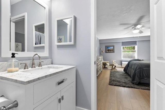 bathroom featuring wood finished floors, a ceiling fan, vanity, and baseboards
