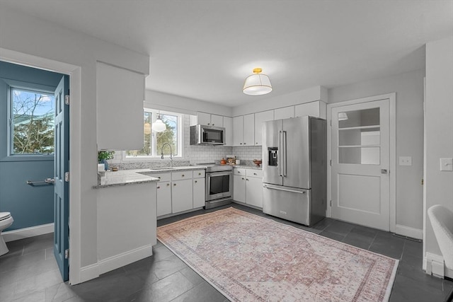1705 Wampanoag Trl, Barrington, RI 02806 - kitchen with appliances with stainless steel finishes, white cabinetry, backsplash, and baseboards