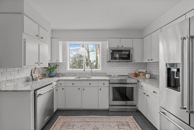 1705 Wampanoag Trl, Barrington, RI 02806 - kitchen featuring appliances with stainless steel finishes, a sink, dark tile patterned flooring, decorative backsplash, and white cabinetry