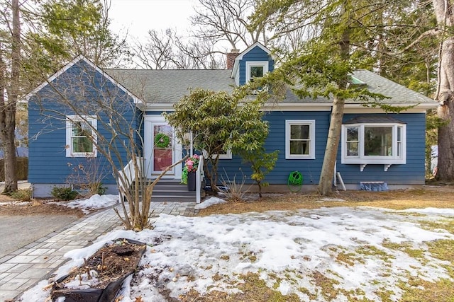 new england style home featuring a shingled roof and a chimney