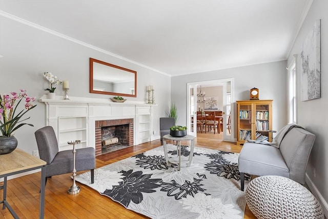 living room featuring ornamental molding, a brick fireplace, wood finished floors, and baseboards