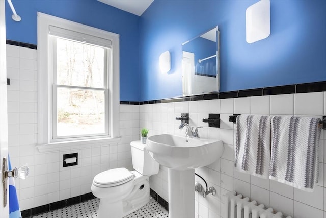 bathroom with wainscoting, toilet, radiator heating unit, walk in shower, and tile walls