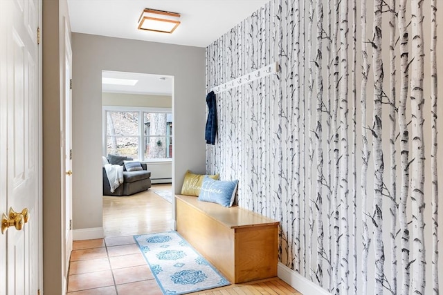 hall featuring a baseboard radiator, light tile patterned flooring, and baseboards