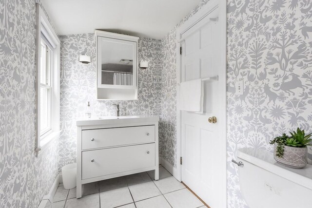 bathroom featuring toilet, vanity, tile patterned flooring, baseboards, and wallpapered walls