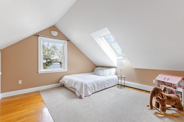 bedroom featuring lofted ceiling with skylight, wood finished floors, and baseboards