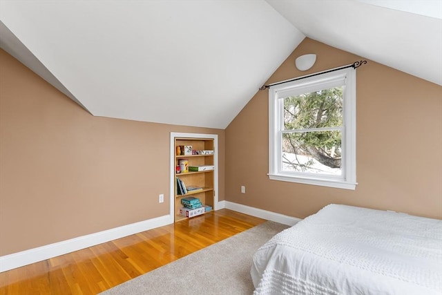 bedroom with lofted ceiling, wood finished floors, and baseboards