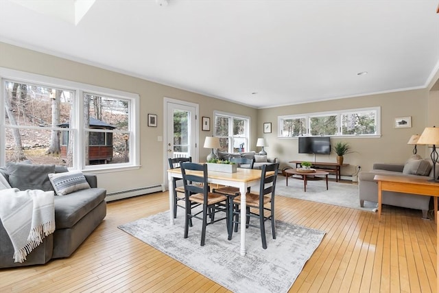 dining space featuring light wood-style floors, a baseboard heating unit, and ornamental molding