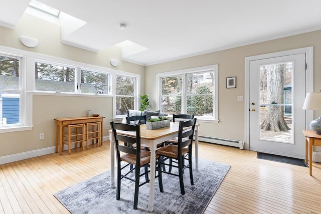 dining space with baseboards, a skylight, a baseboard radiator, and light wood-style floors