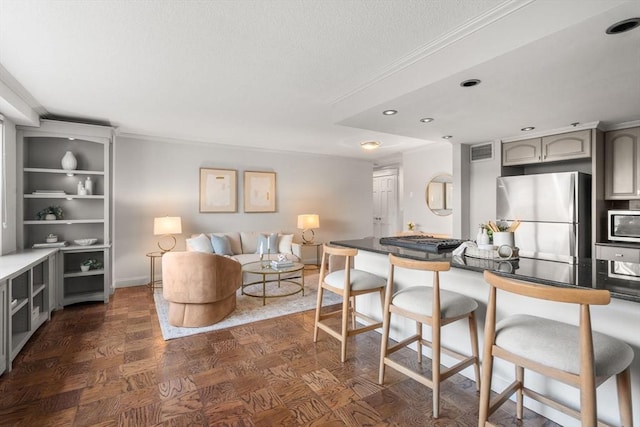 151 Tremont St Unit 8S, Boston, MA 02111 - kitchen with a breakfast bar area, visible vents, crown molding, gray cabinetry, and stainless steel appliances