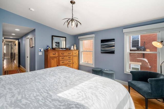 bedroom featuring baseboards, vaulted ceiling, multiple windows, and wood finished floors