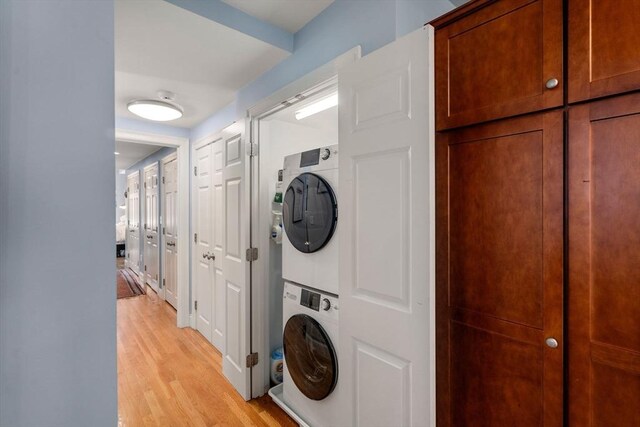 laundry area featuring laundry area, stacked washer / dryer, and light wood-type flooring