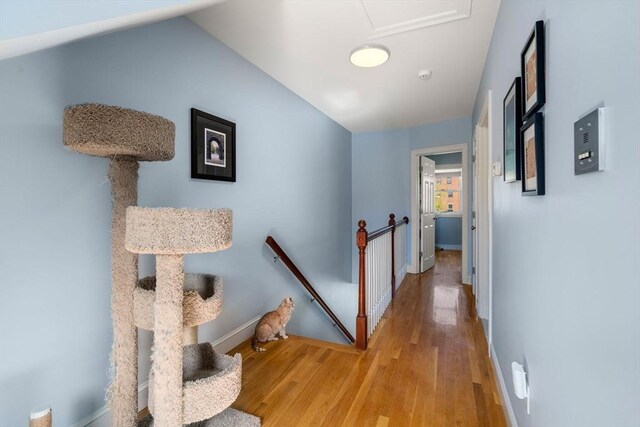 hallway with baseboards, lofted ceiling, wood finished floors, and an upstairs landing