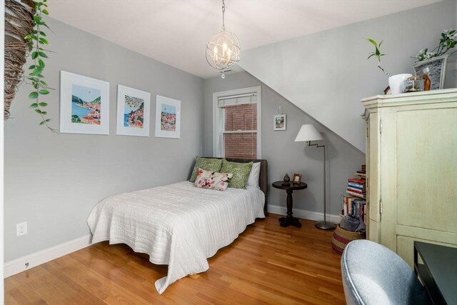 bedroom with baseboards, a chandelier, and wood finished floors