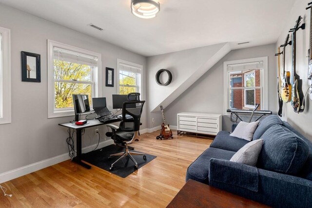 office with light wood-style floors, baseboards, and visible vents