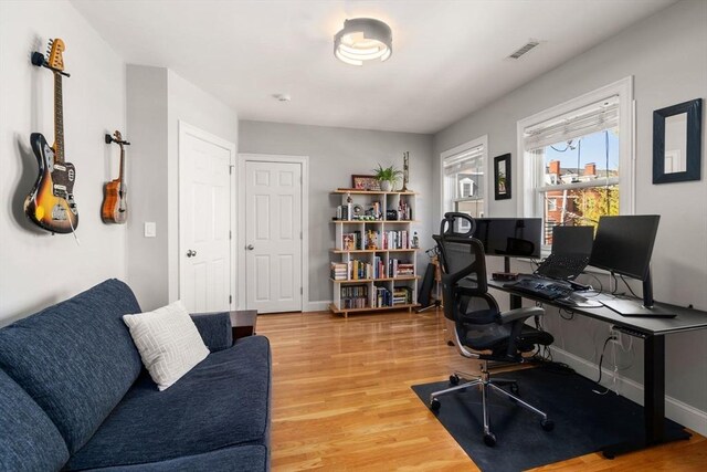 home office with baseboards, wood finished floors, and visible vents