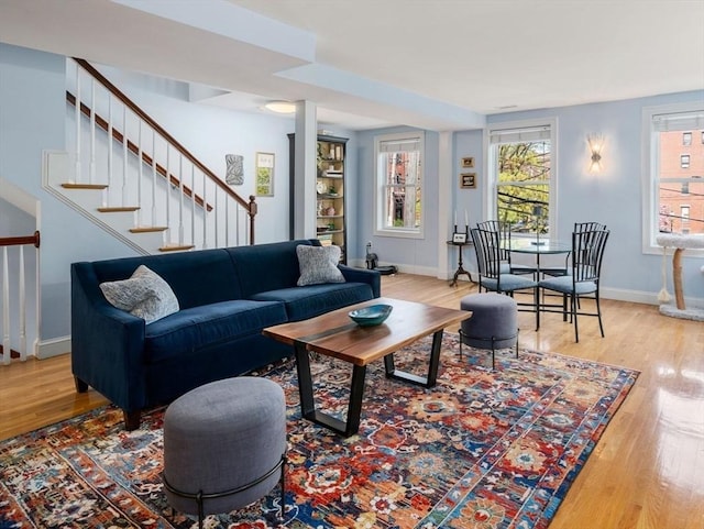living area featuring baseboards, wood finished floors, and stairway