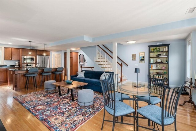 dining room with light wood-type flooring, stairs, and visible vents