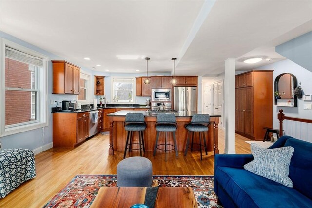 kitchen featuring a kitchen breakfast bar, dark countertops, appliances with stainless steel finishes, and light wood-type flooring