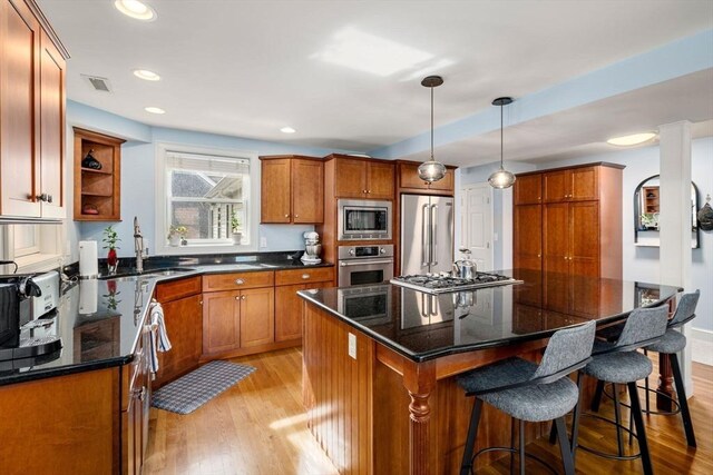 kitchen featuring visible vents, light wood finished floors, a kitchen island, and stainless steel appliances
