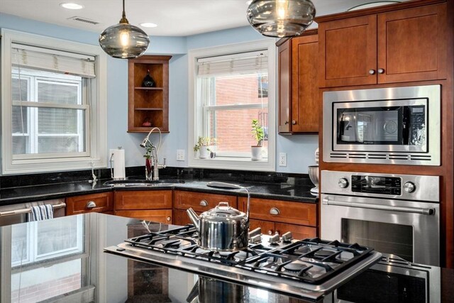 kitchen featuring brown cabinets, open shelves, stainless steel appliances, decorative light fixtures, and visible vents