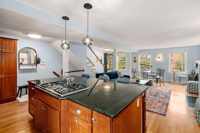 kitchen with brown cabinetry, a center island, light wood-type flooring, open floor plan, and stainless steel gas stovetop