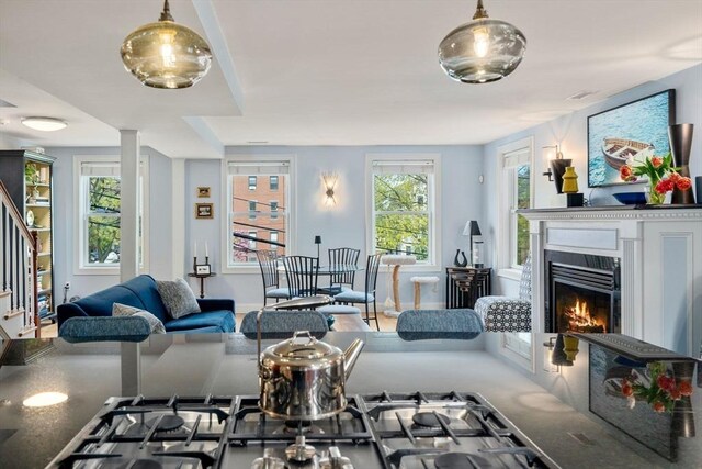 living area featuring visible vents, stairs, and a warm lit fireplace