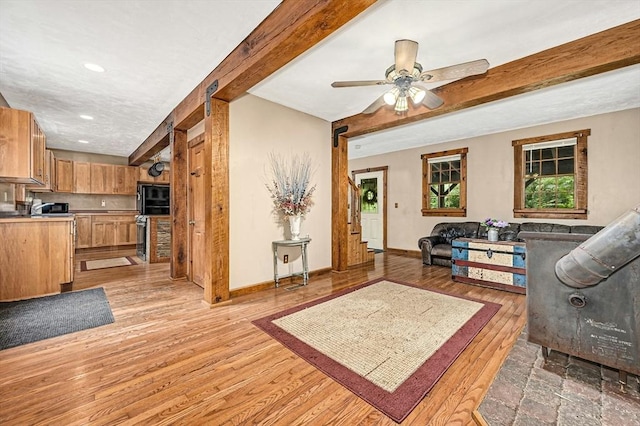 living room featuring beamed ceiling, ceiling fan, and light hardwood / wood-style floors