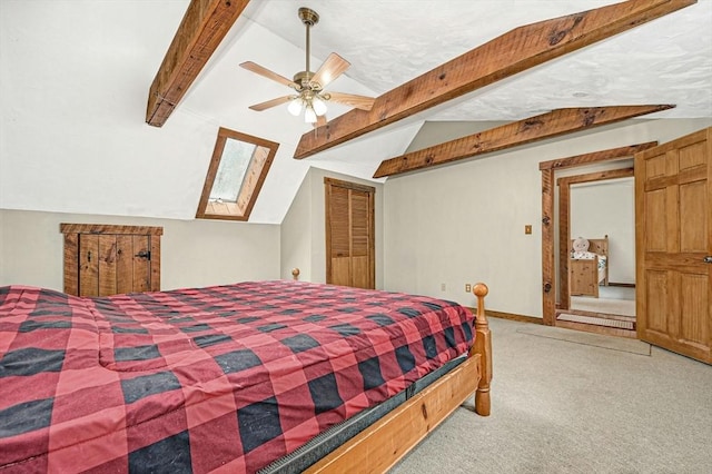 bedroom featuring ceiling fan, a closet, vaulted ceiling with skylight, and carpet