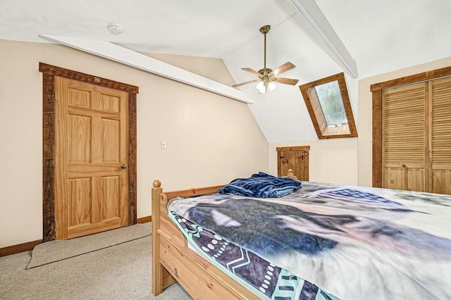 bedroom featuring lofted ceiling with skylight, light carpet, ceiling fan, and a closet