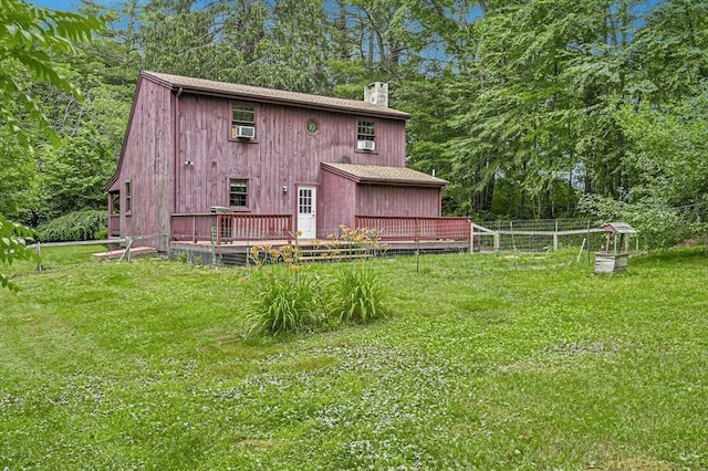 back of house with a wooden deck and a lawn