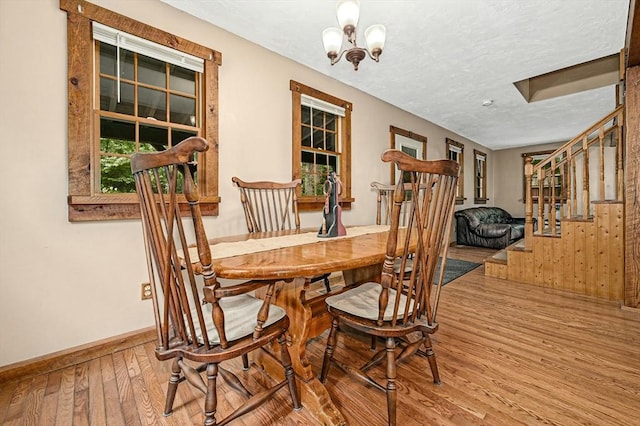 dining space with hardwood / wood-style floors, a notable chandelier, and a textured ceiling