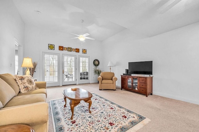 living room featuring light carpet, a towering ceiling, and ceiling fan